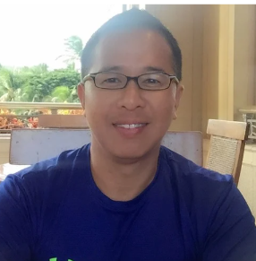 a person with glasses and a blue shirt sitting at a table